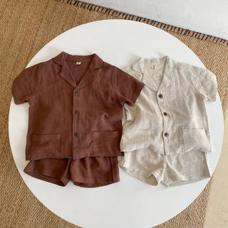 Two children's outfits, one brown and one beige, on a white circular platform.